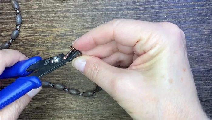 Secure the French wire closure: add a crimp bead, attach the French wire, add the toggle clasp, and crimp it down.