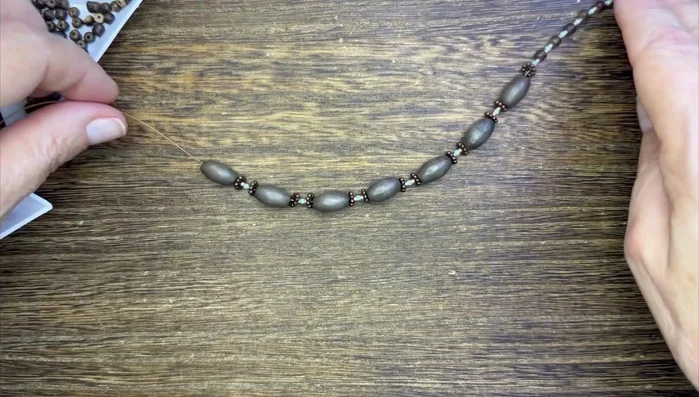 String seed beads onto the beading wire as spacers between the wood and ceramic beads. Use a combination of colors for visual interest.