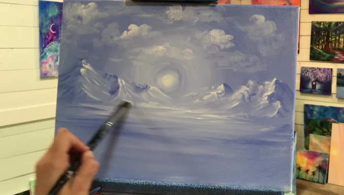 Add bushes and foliage. Use a mop brush and white paint, tapping to create bushes at the base of the mountains. Use a larger mop brush for bushes in the foreground to create perspective.