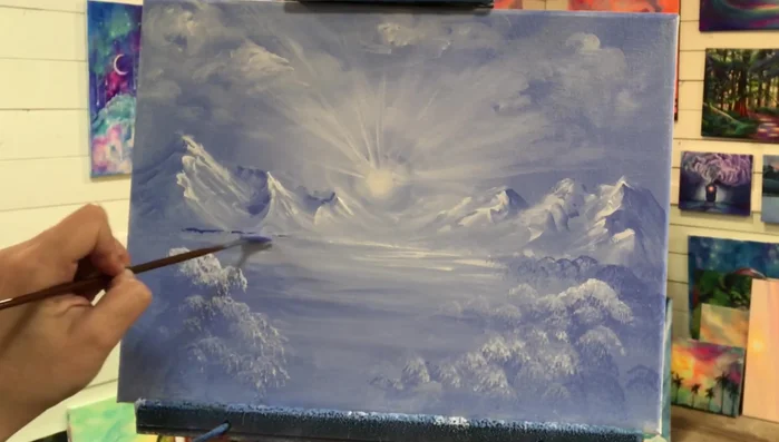 Paint trees. Use a fan brush and ultramarine blue, using light flicks and taps to create trees in the distance. Use a smaller brush for details like branches.