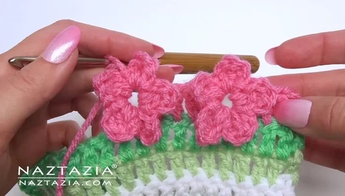 Continue across the row using this pattern. After the chain one, make one double crochet in the next four stitches, then make the two double crochet v-stitch in the next stitch, and proceed with another flower.