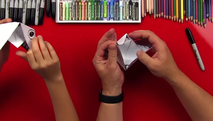 Open the mouth, folding down the tongue flap and tucking the corner to keep it flat.