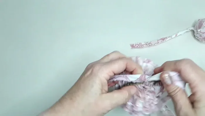 Tie a long piece of fabric around the center to secure the pompom.