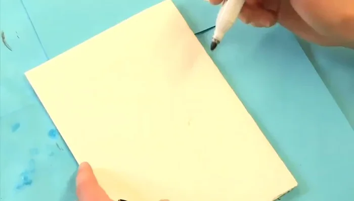 Draw the facial features (nose, eyes, eyebrows, mouth, chin) onto the folded paper. This will create symmetrical features when unfolded.