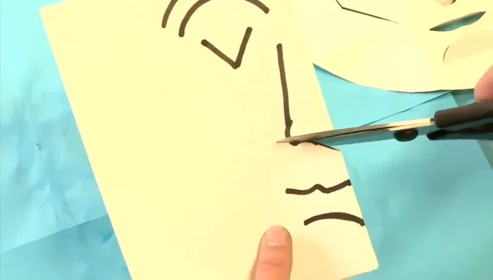 Cut along the drawn lines, carefully cutting out the eye, eyebrow, and mouth shapes. You can fold and refold the paper to make cutting easier.