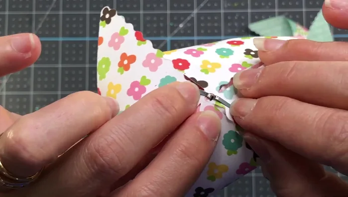 Push the brad through the center hole and secure it.