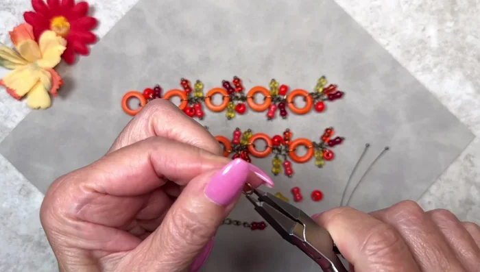 Assemble Strand: Attach multiple dangles to chain links, leaving two links between each group of dangles. Each strand should have 2 links with 2 dangles each. 