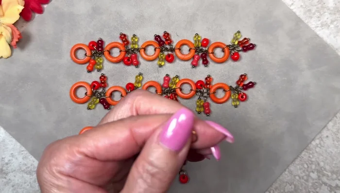 Attach Coconut Rings: Open jump rings, slide a strand of dangles and a coconut ring onto each jump ring, and close the rings. Attach these to the ends of the chain strands. 