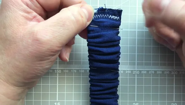 Machine stitch a line of zigzag stitches down the center of the strap using pins as guides. Stretch the fabric between pins to keep the gathers even while stitching.