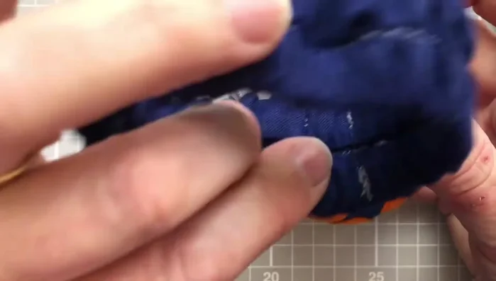 Attach the finished strap to the toadstool lid using hand-sewing techniques.